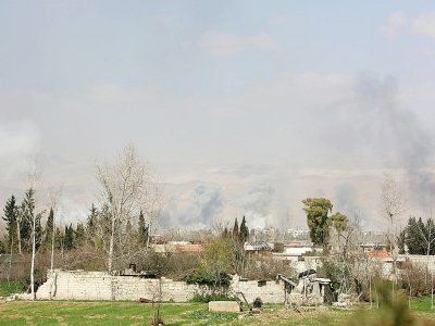 Photo prise depuis les positions des forces du régime syrien montrant de la fumée qui s'élève au-dessus de la ville de Jisrine, dans l'enclave rebelle assiégée de la Ghouta orientale, le 11 mars 2018 - STRINGER [AFP]