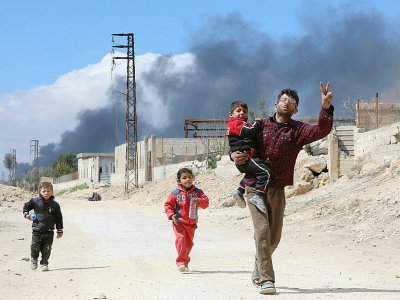 Un Syrien et des enfants sortent de la localité de Hammouriyé dans l'enclave rebelle de la Ghouta orientale, cible d'une offensive du régime, le 16 mars 2018 - STRINGER [AFP]