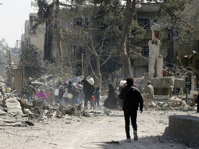 Des civils fuient leurs maisons détruites dans la ville de Hammouriyé dans le secteur rebelle de la Ghouta orientale, cible d'une offensive du régime syrien, le 15 mars 2018 - ABDULMONAM EASSA [AFP]