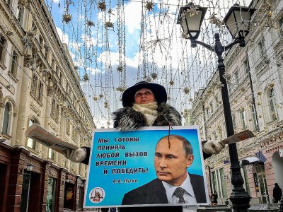Une militante distribue des tracts en faveur de Vladimir Poutine dans une rue de Moscou, le 16 mars 2018 - Yuri KADOBNOV [AFP]