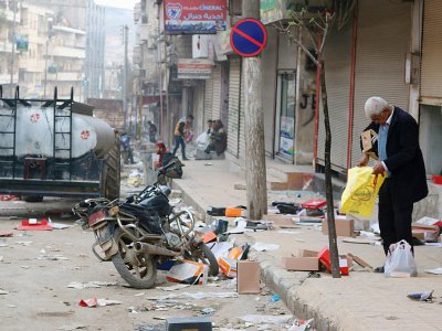 Un homme examine des cartons et des sacs dans une rue de la ville d'Afrine, reprise par les forces turques et leurs alliés rebelles syriens et où des pillages ont eu lieu, le 19 mars 2018 - STRINGER [AFP]