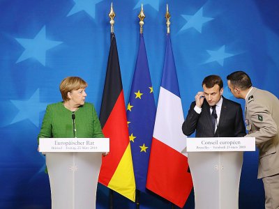 Le président français Emmanuel Macron, informé de la prise d'otages à Trèbes, pendant une conférence de presse avec la chancelière allemande Angela Merkel à Bruxelles le 23 mars 2018 - Ludovic MARIN [AFP]