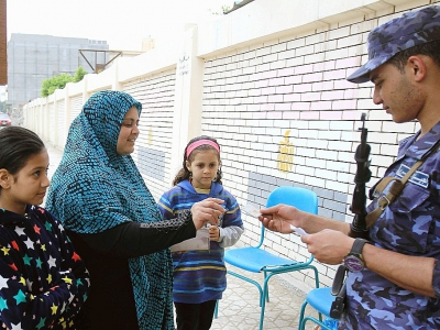 Un soldat contrôle la pièce d'identité d'une Egyptienne à l'entrée d'un bureau de vote d'un quartier d'Alexandrie (nord), lors de la troisième et dernière journée de l'élection présidentielle, le 28 mars 2018 - STRINGER [AFP]