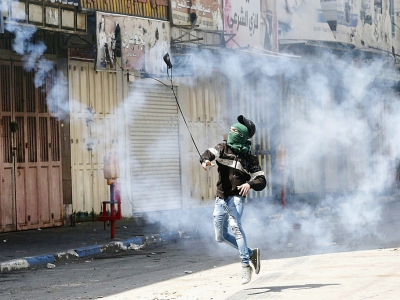 Un manifestant palestinien renvoie une cartouche de gaz lacrymogène sur des soldats israéliens le 31 mars 2018 à Hébron, en Cisjordanie - HAZEM BADER [AFP]