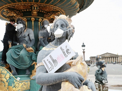 Un militant pose des masques le 31 mars 2018 devant la bouche de statues place de la Concorde, afin de dénoncer l'inaction des pouvoirs publics contre la pollution de l'air - JACQUES DEMARTHON [AFP]