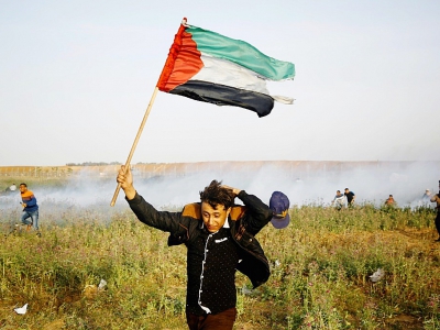 Un Palestinien brandissant un drapeau lors d'une manifestation à la frontière entre la bande de Gaza et Israël le 4 avril 2018 - MOHAMMED ABED [AFP]
