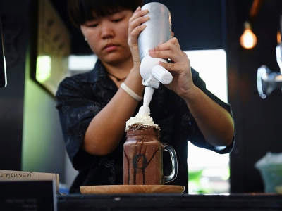 Une employée du Café de prise de conscience de la mort prépare un milkshake au chocolat baptisé "mort", à Bangkok, le 30 mars 2018 - LILLIAN SUWANRUMPHA [AFP]