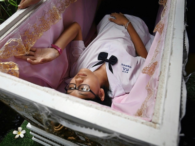 Une adolescente thaïlandaise s'allonge dans le cercueil du "café de la mort", à Bangkok, le 30 mars 2018 - LILLIAN SUWANRUMPHA [AFP]