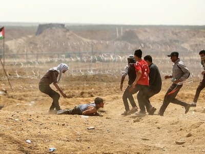 Des Palestiiens viennent en aide à un manifestant blessé lors d'affrontements avec les forces israéliennes près de la frontière avec la bande de Gaza, à l'est de la ville de Gaza, le 13 avril 2018 - MAHMUD HAMS [AFP]