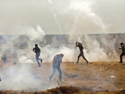 Des Palestiniens fuient les gaz lacrymogènes tirés par les soldats israéliens lors de protestations à la frontière entre Israël et la bande de Gaza, le 13 avril 2018 - MAHMUD HAMS [AFP]