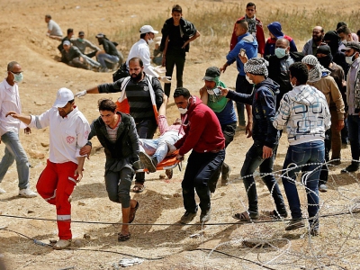 Evacuation d'un manifestant palestinien blessé par les forces de sécurité israéliennes près de la frontière entre Gaza et l'Etat hébreu, le 13 avril 2018 - MAHMUD HAMS [AFP]