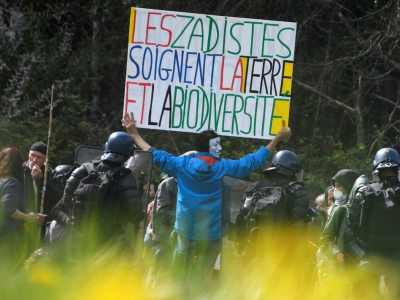 Un manifestant tient une pancarte face aux forces de l'ordre sur le site de la Zad de Notre-Dame-des-Landes, le 15 avril 2018 - Damien MEYER [AFP]