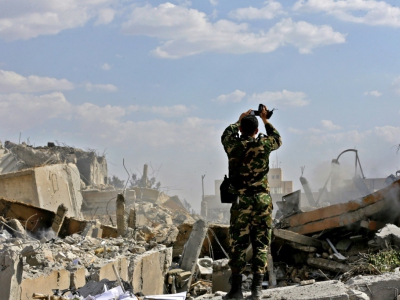 Un soldat syrien photographie les décombres d'un bâtiment faisant partie d'un centre de recherches dans le nord de Damas visé par des frappes américaines, françaises et russes en représailles à une attaque chimique présumée, le 14 avril 2018, lors d' - LOUAI BESHARA [AFP]