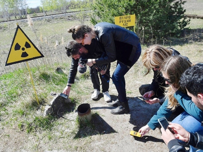 Des touristes mesurent le degré de radioactivité dans la "forêt rouge" devant le réacteur Numéro 4 de Tchernobyl, le 23 avril 2018 - Sergei SUPINSKY [AFP]