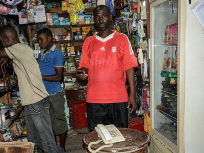 Ernest Nshimirimana pose dans son kiosque de Bujumbura au côté de son téléphone fixe blanc, le 25 avril 2018 au Burundi - Onesphore NIBIGIRA [AFP]