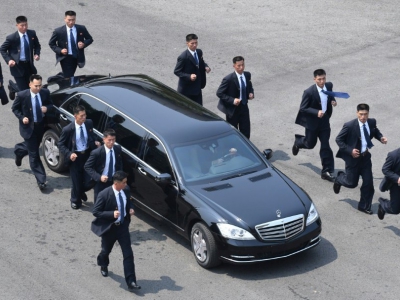 Des gardes du corps accompagnent en courant la voiture transportant le leader nord-coréen Kim Jong-Un après une session matinale de discussions au village de Panmunjom, le 27 avril 2018 - Korea Summit Press Pool [Korea Summit Press Pool/AFP]