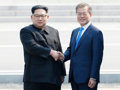 Moon Jae-in (d) et Kim Jong Un se serrent la main sur la ligne de démarcation avant le début du sommet, le 27 avril 2018 à Panmunjom - Korea Summit Press Pool [Korea Summit Press Pool/AFP/Archives]