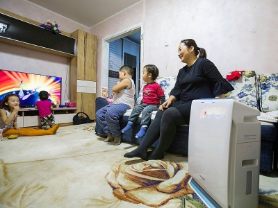 Munguntuul Batbayar, comptable, regarde la télévision avec ses enfants à proximité d'un purificateur d'air chez elle, le 20 janvier 2018 à Oulan-Bator, en Mongolie - BYAMBASUREN BYAMBA-OCHIR [AFP]