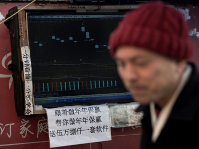 Un boursicoteur explique la volatilité des cours devant son ordinateur à Shanghai, le 25 mars 2018 - Johannes EISELE [AFP]