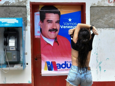 Une femme soulève son tee-shirt devant une affiche de campagne du président vénézuélien, Nicolas Maduro, dans l'Etat de Choroni-Aragua, au Vénézuela, le 12 mai 2018 - JUAN BARRETO [AFP]