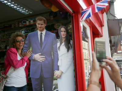 Une touriste pose avec un portrait en carton du prince Harry et de sa fiancée Meghan Markle à Windsor le 8 mai 2018 - Daniel LEAL-OLIVAS [AFP/Archives]