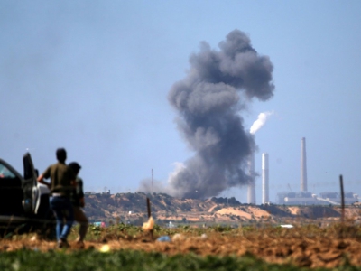Des Palestiniens regardent une colonne de fumée s'élever après un bombardement de l'armée israélienne sur un site militaire du mouvement islamiste Hamas, le 14 mai 2018 dans la bande de Gaza - Mohammed ABED [AFP]