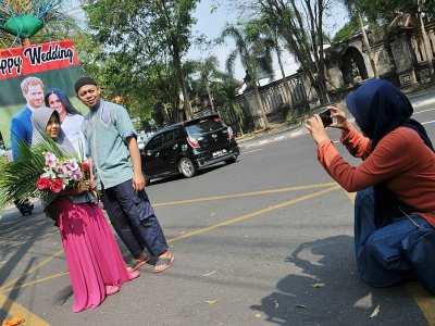 Un couple d'Indonésiens posent devant un portrait des mariés dans une rue de Solo, dans l'île de Java, le 20 mai 2018 - ANWAR MUSTAFA [AFP]
