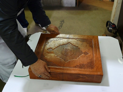 L'Afghan Mohammad Tamim Sahibzada, maître ès miniatures et responsable des enluminures, montre un Coran en soie dans les 610 pages ont été peintes à la main, le 19 avril 2018 à la Fondation britannique Turquoise Mountain, à Kaboul - WAKIL KOHSAR [AFP]