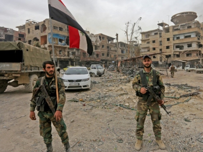Des membres des forces progouvernementales portent un drapeau syrien dans le quartier de Hajar al-Aswad repris aux jihadistes du groupe Etat islamique, le 22 mai 2018 - LOUAI BESHARA [AFP]
