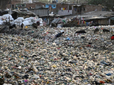 Un chiffonier dans un canal d'évacuation des égoûts rempli de déchets plastiques dans le bidonville Taimur Nagar à New Delhi le 30 mai 2018 - Dominique FAGET [AFP]