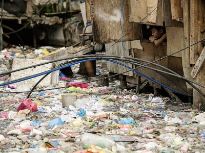 Un garçon regarde des déchets dans un bidonville de Manille, le 12 mai 2018 - NOEL CELIS [AFP]