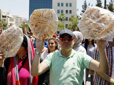 Des Jordaniens brandissent du pain sur lequel est écrit "corruption = faim" lors d'une manifestation contre l'austérité et la cherté de la vie, le 6 juin à Amman - AHMAD GHARABLI [AFP]