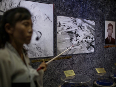 Une guide montre à des visiteurs des photos d'ossements au musée des atrocités de guerre américaines, le 24 juillet 2018 à Sinchon, en Corée du Nord - Ed JONES [AFP]