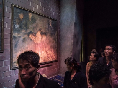 Un groupe de visiteurs passe devant un tableau représentant des soldats américains brûlant un Nord-Coréen, le 24 juillet 2017 au Musée des atrocités de guerre américaines à Sinchon, en Corée du Nord - Ed JONES [AFP]