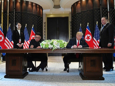 Le leader nord-coréen Kim Jong Un (g) et le président américain Donald Trump (d) signent un document en présence du secrétaire d'Etat américain Mike Pompeo et de la soeur du dirigeant nord-coréen Kim Yo Jong, le 12 juin 2018 à l'hôtel Capella, sur l' - SAUL LOEB [AFP]