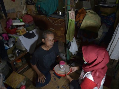Une bénévole du projet "Un bienfait partagé" apporte à un homme des restes de nourriture de cérémonies de mariage, le 20 mars 2018 à Jakarta, en Indonésie - Adek BERRY [AFP]