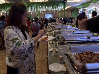 Une invitée se sert à manger à un buffet lors d'un mariage dans un hôtel de Jakarta, le 19 mars 2018 en Indonésie - Adek BERRY [AFP]