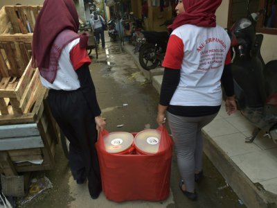 Des bénévoles du projet "Un bienfait partagé" distribuent à des pauvres des restes de nourriture de cérémonies de mariage, le 20 mars 2018 à Jakarta, en Indonésie - Adek BERRY [AFP]