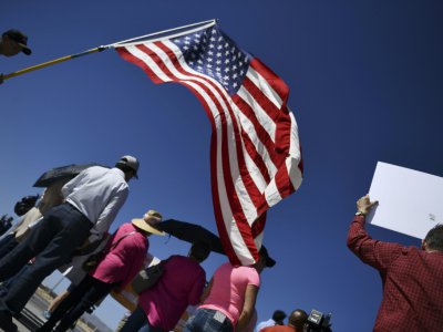 Des manifestants déploient le drapeau américain lors d'un rassemblement près d'un poste-frontière avec le Mexique, au Texas, pour protester contre les séparations de familles de migrants, le 21 juin 2018 - Brendan Smialowski [AFP]