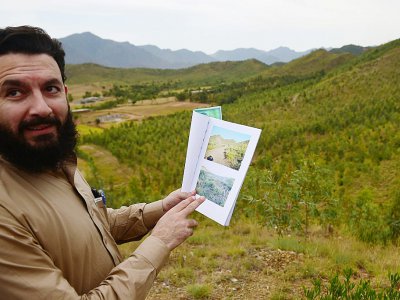 Pervaiz Manan, responsable forestier, montre des photos de la zone avant le programme de reboisement, le 17 mai 2018 à Heroshah, dans la vallée du Swat, au Pakistan - FAROOQ NAEEM [AFP]