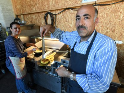 Jawad (g) et Zainab Al-Khajee, couple de journalistes irakiens réfugiés en France, préparent des plats irakiens, le 23 juin 2018 dans le snack de Darwin, un espace associatif sur les bords de la Garonne, à Bordeaux - MEHDI FEDOUACH [AFP]