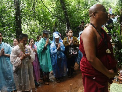 Un moine bouddhiste et des familles des enfants coincés dans une grotte prient à Chiang Rai, le 27 juin 2018 - LILLIAN SUWANRUMPHA [AFP]