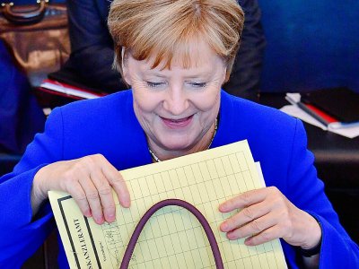 La chancelière allemande Angela Merkel sort un dossier de son sac avant une réunion du groupe parlementaire CDU/CSU à Berlin, le 2 juillet 2018 - John MACDOUGALL [AFP]
