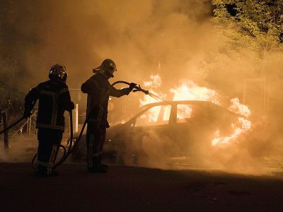 Un pompier lutte contre les flammes d'une voiture incendiée dans le quartier Malakoff de Nantes, le 4 juillet 2018 - SEBASTIEN SALOM GOMIS [AFP]