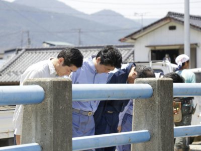 Le Premier ministre Shinzo Abe (2e g) et le gouverneur de la préfecture d'Ehime, Tokihiro Nakamura (g), prient pour les victimes des inondations et glissements de terrain, le 13 juillet 2018 à Seiyo - JAPAN POOL VIA JIJI PRESS [JIJI PRESS/AFP]