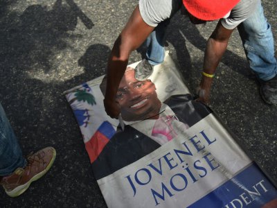 Un manifestant découpe un portrait du président haïtien Jovenel Moise, le 7 juillet 2018 à Port-au-Prince - HECTOR RETAMAL [AFP/Archives]