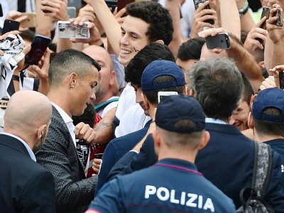 La recrue star de la Juventus Cristiano Ronaldo signe des autographes, à son arrivée au centre médical du club, le 16 juillet 2018 à Turin - Miguel MEDINA [AFP]