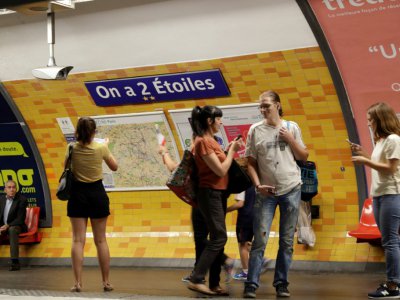 Des passagers du métro de Paris photographient l'affiche "On a deux étoiles", en référence à la 2e Coupe du Monde de la France, à la station de l'Etoile le 16 juillet 2018 - Thomas SAMSON [AFP]