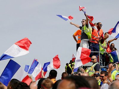 Du personnel de l'aéroport de Roissy accueille les Bleus avec des drapeaux tricolores, le 16 juillet 2018 - Thomas SAMSON [AFP]