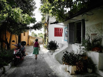 Une habitante dans une ruelle d'Anafiotika, un quartier situé dans la zone archéologique de l'Acropole, le 6 juillet 2018 à Athènes, en Grèce - LOUISA GOULIAMAKI [AFP]